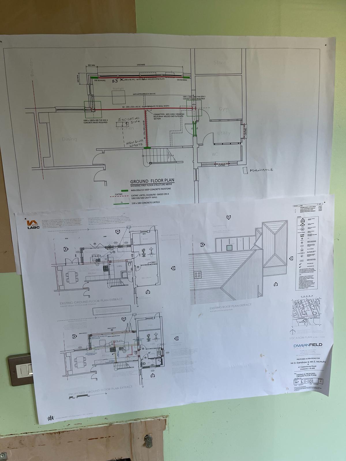 Proposed ground floor plan drawings taped to a wall on site